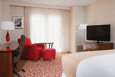 a hotel room with red chairs and a tv
