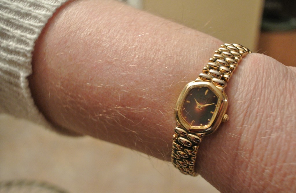 a wrist with a gold watch